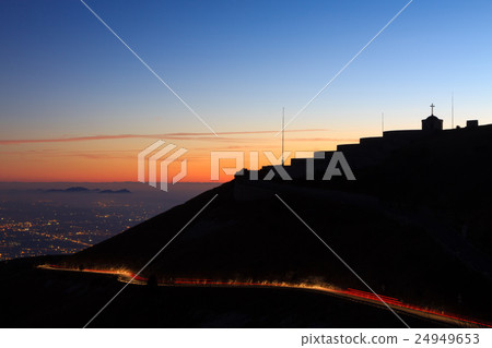 Light trails with building in silhouette. 24949653