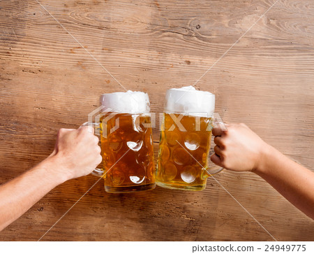 Two unrecognizable men clinking with beer mugs Two unrecognizable men clinking with beer mugs 24949775