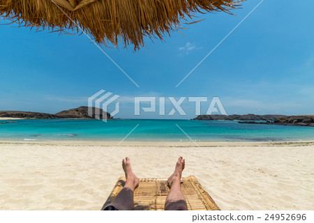 Legs of guy relaxing on beach under umbrella 24952696