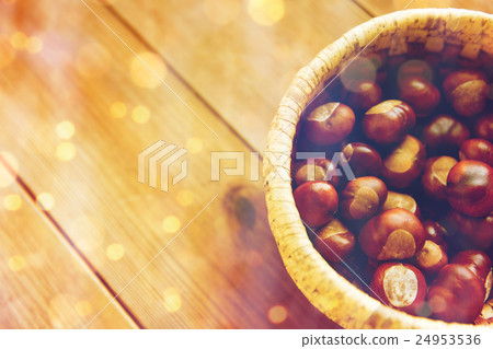 close up of chestnuts in basket on wooden table 24953536