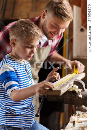 father and son with ruler measure wood at workshop father and son with ruler measure wood at workshop 24954309