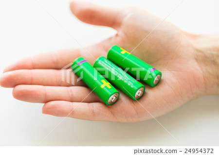 close up of hand holding green alkaline batteries 24954372