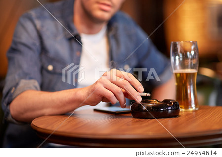 man drinking beer and smoking cigarette at bar 24954614