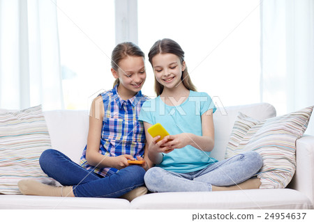 happy girls with smartphones sitting on sofa happy girls with smartphones sitting on sofa 24954637