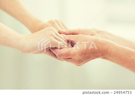 close up of senior and young woman holding hands 24954753