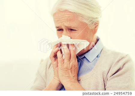 sick senior woman blowing nose to paper napkin 24954759