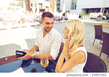 happy couple with wallet paying bill at restaurant happy couple with wallet paying bill at restaurant 24955391