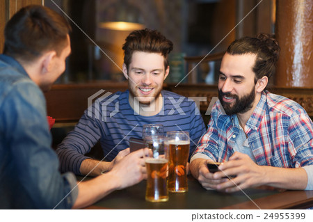 male friends with smartphones drinking beer at bar male friends with smartphones drinking beer at bar 24955399