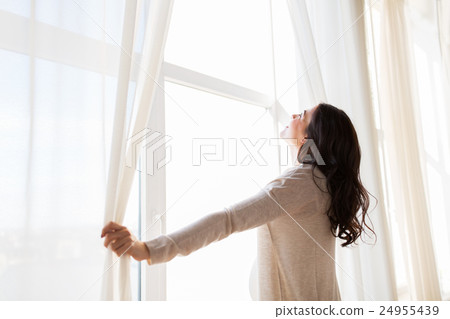 close up of pregnant woman opening window curtains 24955439