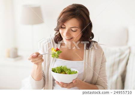 smiling young woman eating salad at home smiling young woman eating salad at home 24955710