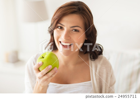 smiling young woman eating green apple at home smiling young woman eating green apple at home 24955711