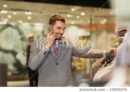 happy man calling on smartphone at clothing store 24956078