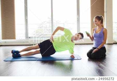 man and woman doing plank exercise on mat in gym 24956272