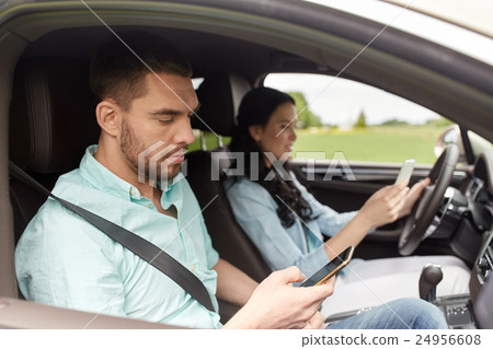 man and woman with smartphones driving in car 24956608