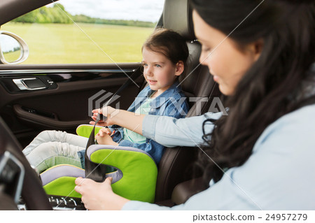 happy woman fastening child with seat belt in car 24957279