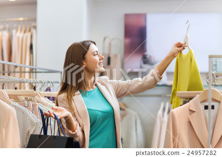 happy young woman choosing clothes in mall 24957282