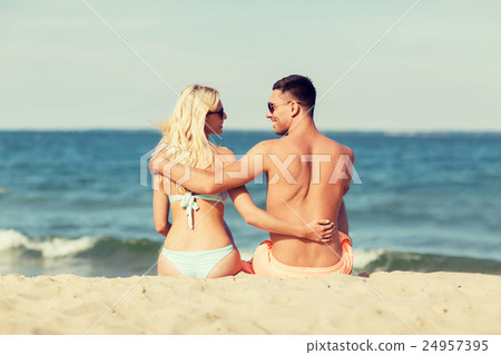 happy couple in swimwear sitting on summer beach 24957395