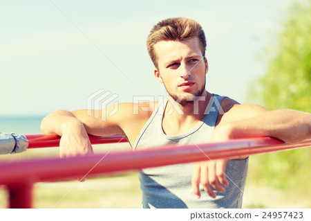 young man exercising on parallel bars outdoors 24957423