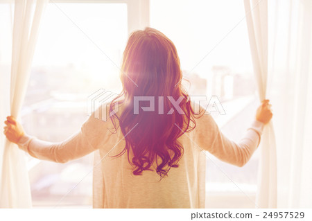 close up of woman opening window curtains 24957529