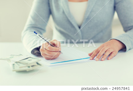 close up of hands with money filling tax form close up of hands with money filling tax form 24957841