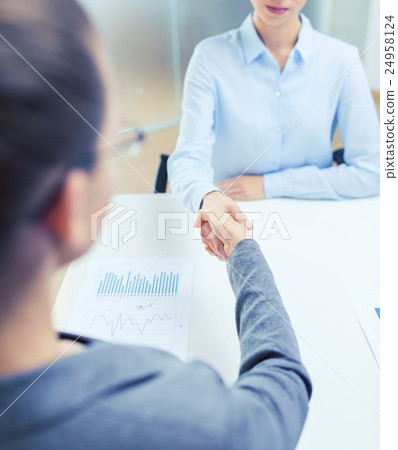 two calm businesswoman shaking hands in office two calm businesswoman shaking hands in office 24958124