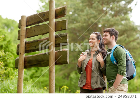 smiling couple at signpost with backpacks hiking 24958371