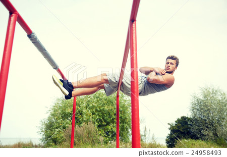 young man doing sit up on parallel bars outdoors 24958493