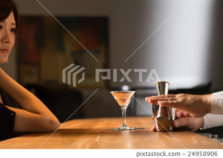 A cocktail-making bartender and a woman 24958906