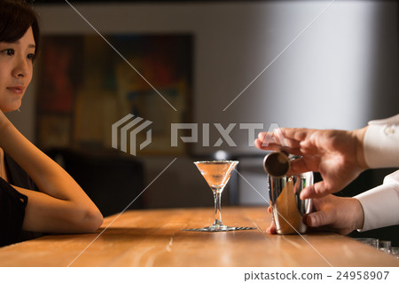 A cocktail-making bartender and a woman 24958907
