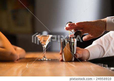 A cocktail-making bartender and a female customer 24958910