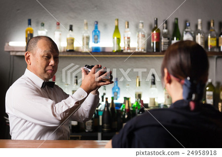 Bartender shaking shaker and female guest 24958918