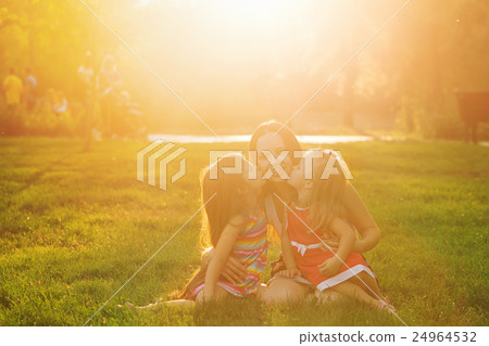 Mother and two daughters embrace and kiss Mother and two daughters embrace and kiss 24964532