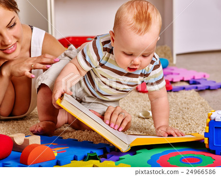 Kid and mother baby boy lying on floor read book. 24966586