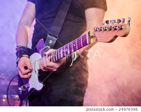 Rock band performs on stage. Guitarist. 24976398