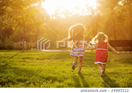 Two sisters running on the lawn Two sisters running on the lawn 24993522