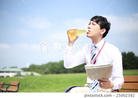 Businessman (male salaried worker 30's office worker bench chair sitting park sunny suit newspaper) 25002392