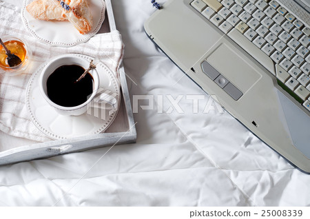 A cup of coffee with the laptop on the bed A cup of coffee with the laptop on the bed 25008339