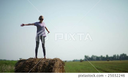 Pretty girl is standing on haystacks Pretty girl is standing on haystacks 25032246