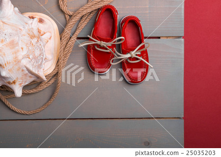 Red boat shoes near big shell and rope on wooden Red boat shoes near big shell and rope on wooden 25035203