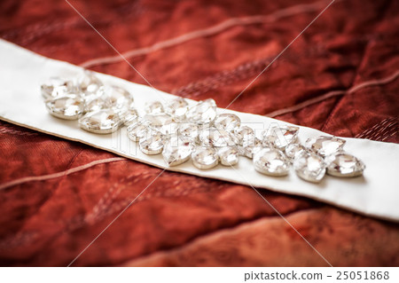 Wedding belt decorated with jewelry on red sofa Wedding belt decorated with jewelry on red sofa 25051868