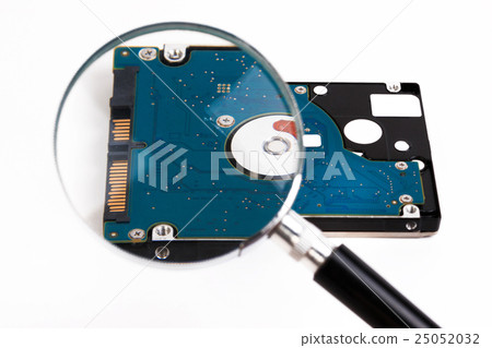 Magnifying glass over a computer hard drive. 25052032
