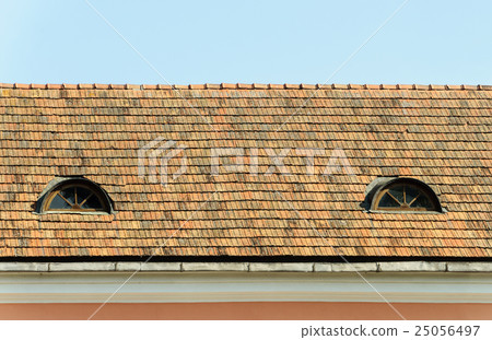 Old tiled roof with two attic windows 25056497