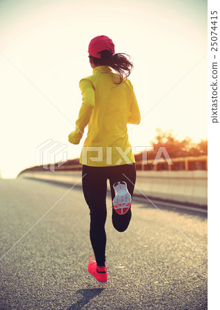 young woman runner running on city road 25074415