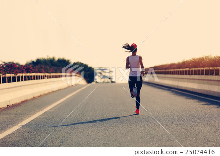 young woman runner running on city road 25074416