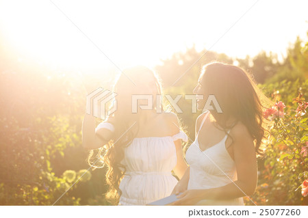 Two sisters looking at each other. Sunset 25077260