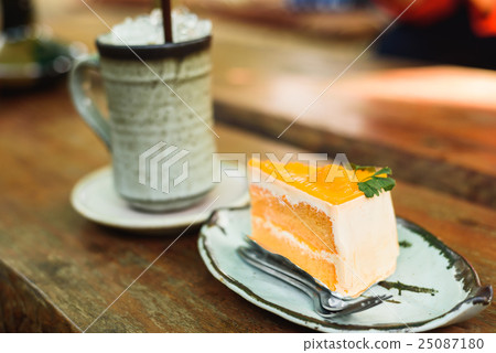 orange cake with ice coffee on wood table 25087180