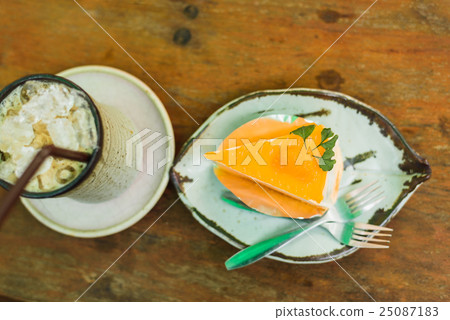 orange cake with ice coffee on wood table 25087183