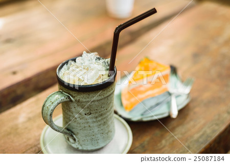 orange cake with ice coffee on wood table 25087184
