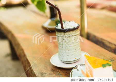 orange cake with ice coffee on wood table 25087194