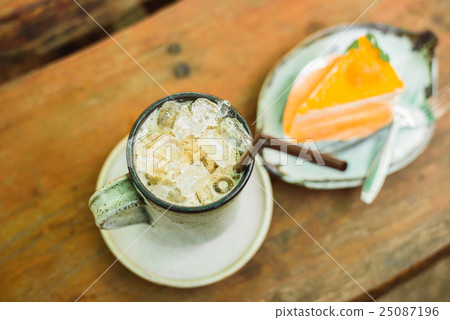 orange cake with ice coffee on wood table 25087196
